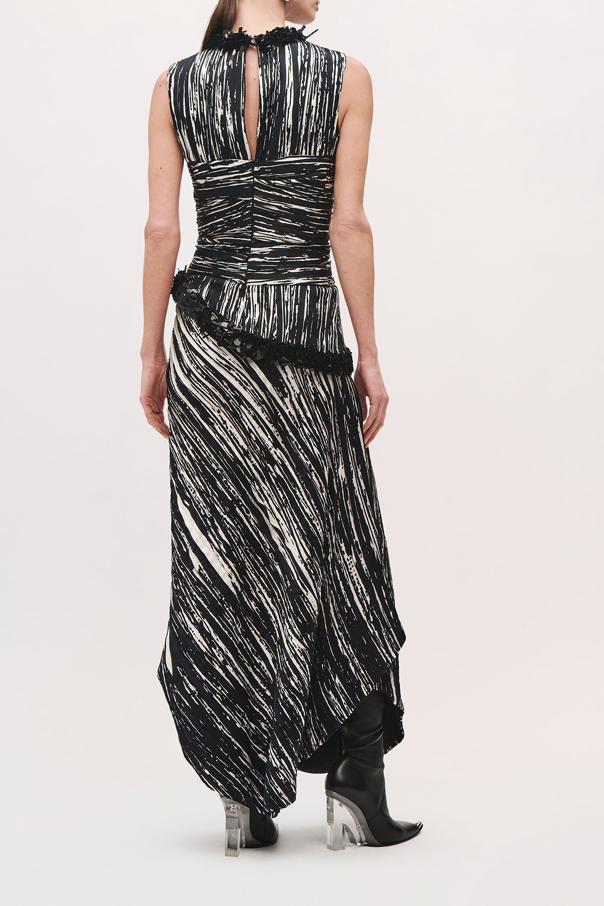 Back product view of a model wearing the Sinclair Dress in Black/White with a keyhole opening, ruched fitted bodice, black sequin trim at the neckline and hips, and an asymmetric floor-length skirt.