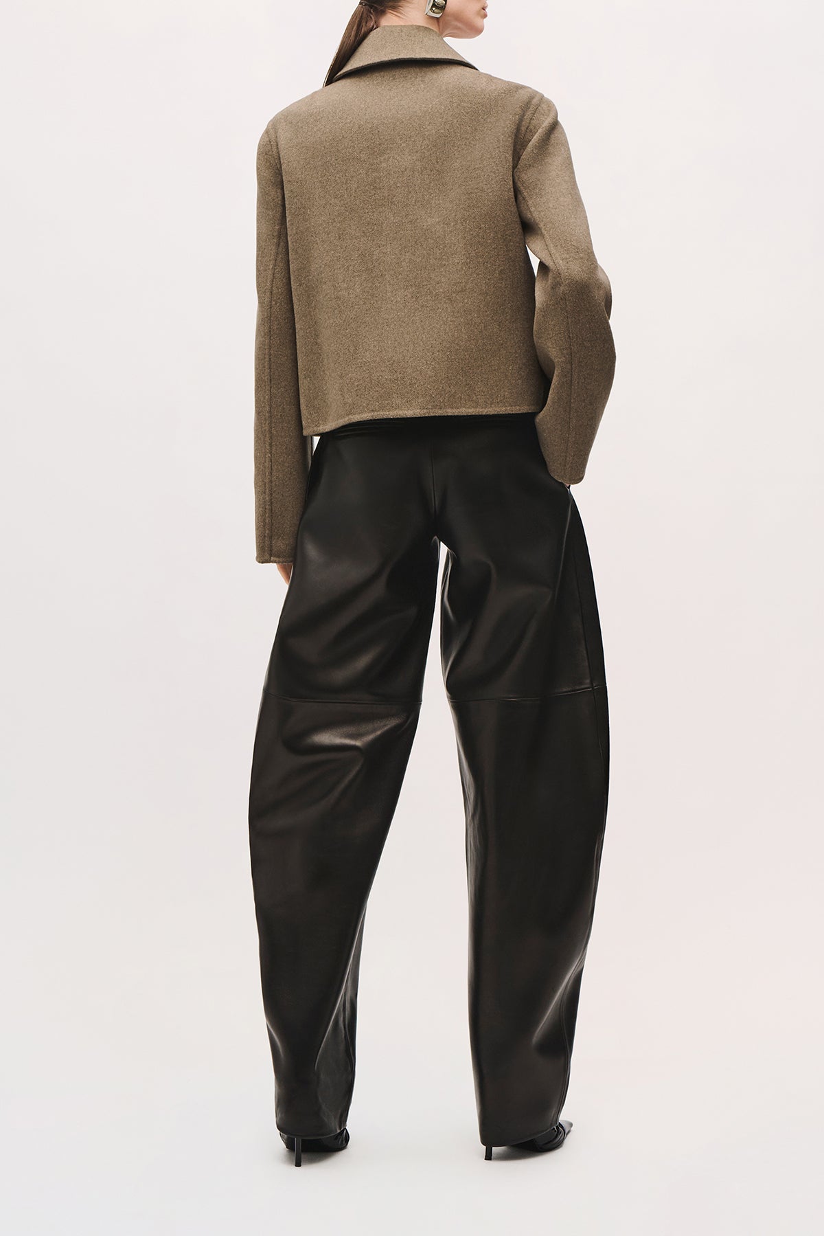 Back view of the Remi Jacket with one hand in a front pocket, and cropped fit.