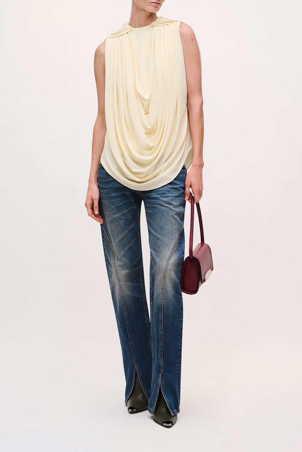 Front View of a model wearing the Astor Top in Butter Yellow, which is sleeveless with a round neckline and gathered draping.