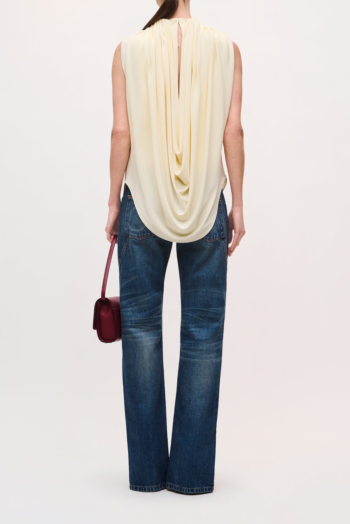 Back View of model wearing the Astor Top with a draped bodice and a narrow keyhole opening at the neck.