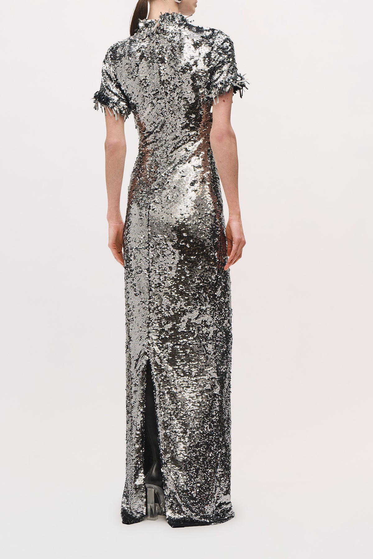 Back view of a model wearing the Bex Gown in Silver, showing its fitted shape and back slit. 