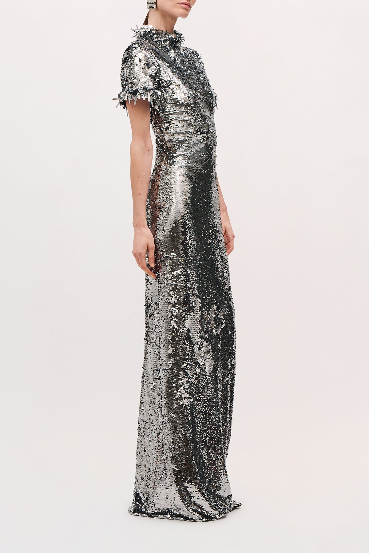 Side view of a model wearing the Bex Gown in Silver, showing its fitted silhouette and floor-length hem.