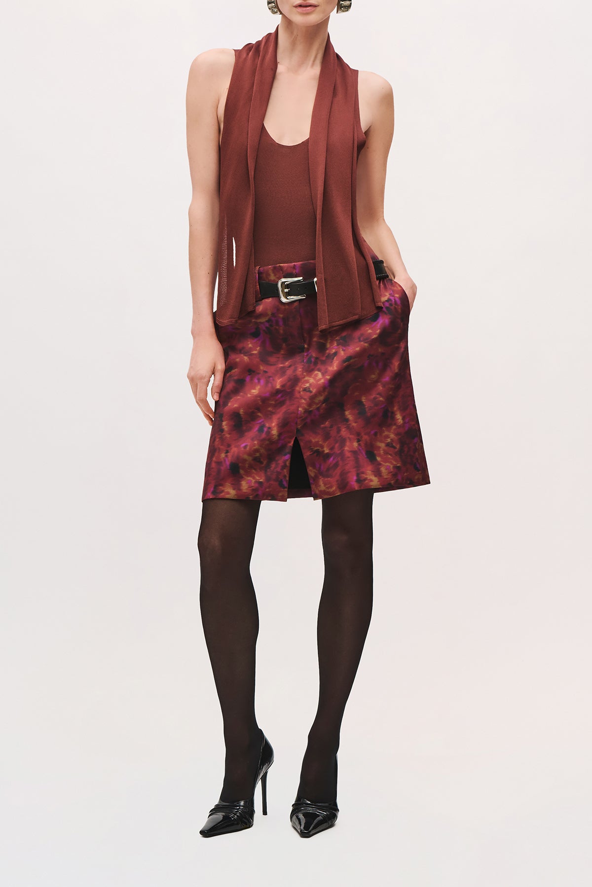Front product view of a model wearing The Capri Bodysuit in Terracotta with cut-off sleeves and an attached scarf draped from the neckline.
