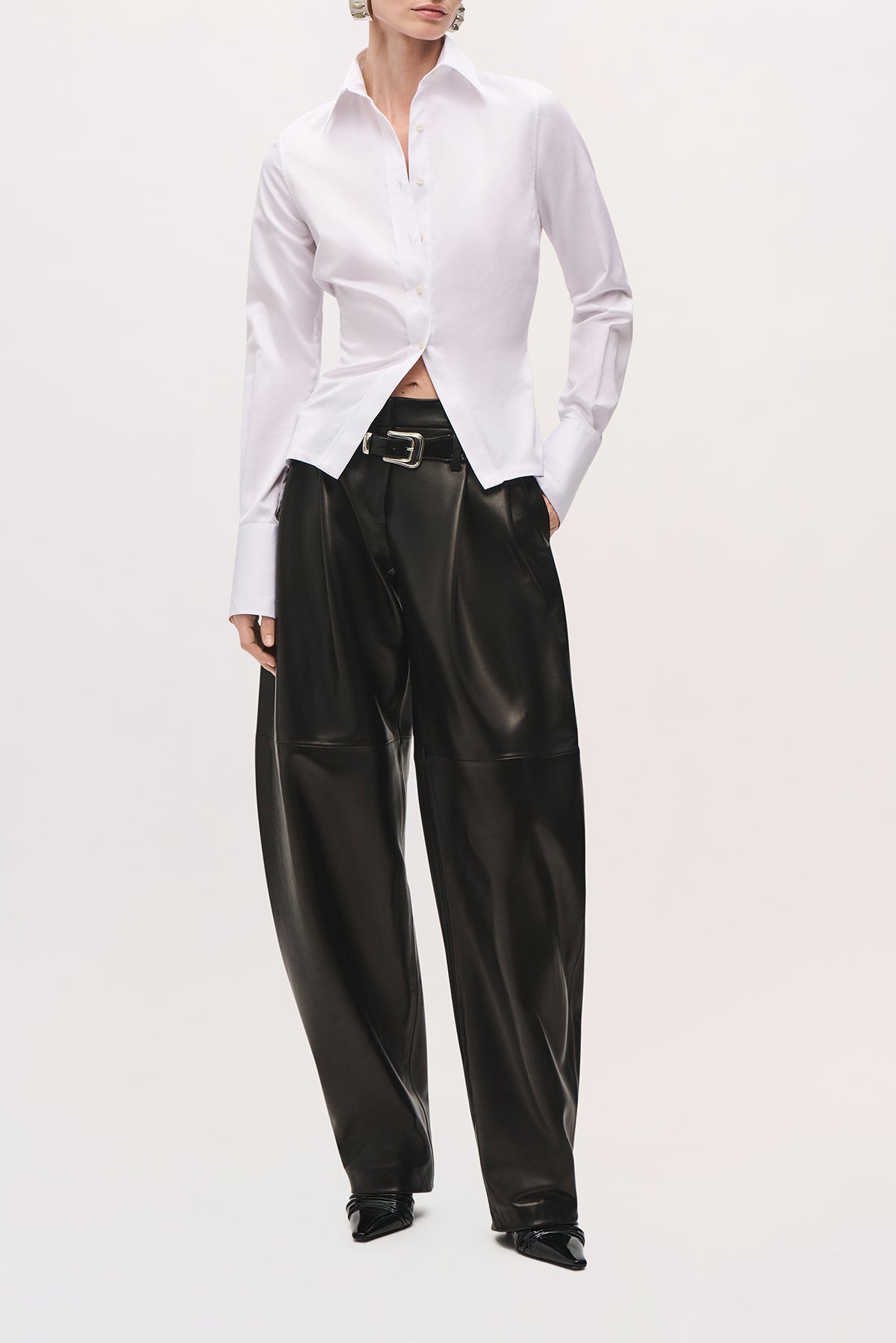Front view of a model wearing the Ceci Button Down in White, a fitted collared shirt with a button-front closure, shaped waist, long sleeves, extended cuffs, and a split front hem.