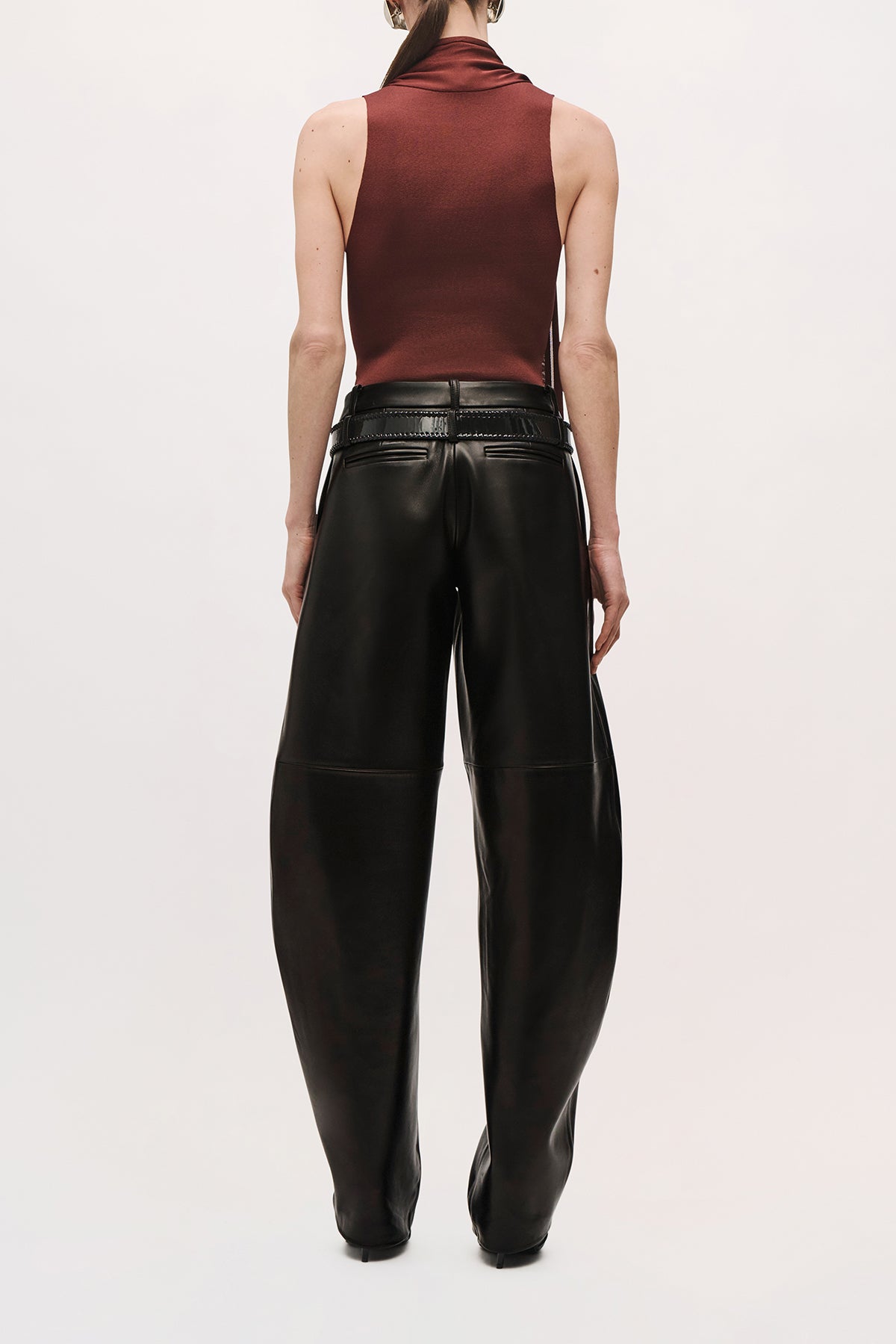 Back product view of a model wearing the Dean Pant in black nappa leather with a low-rise waist and relaxed, curved-leg silhouette,
