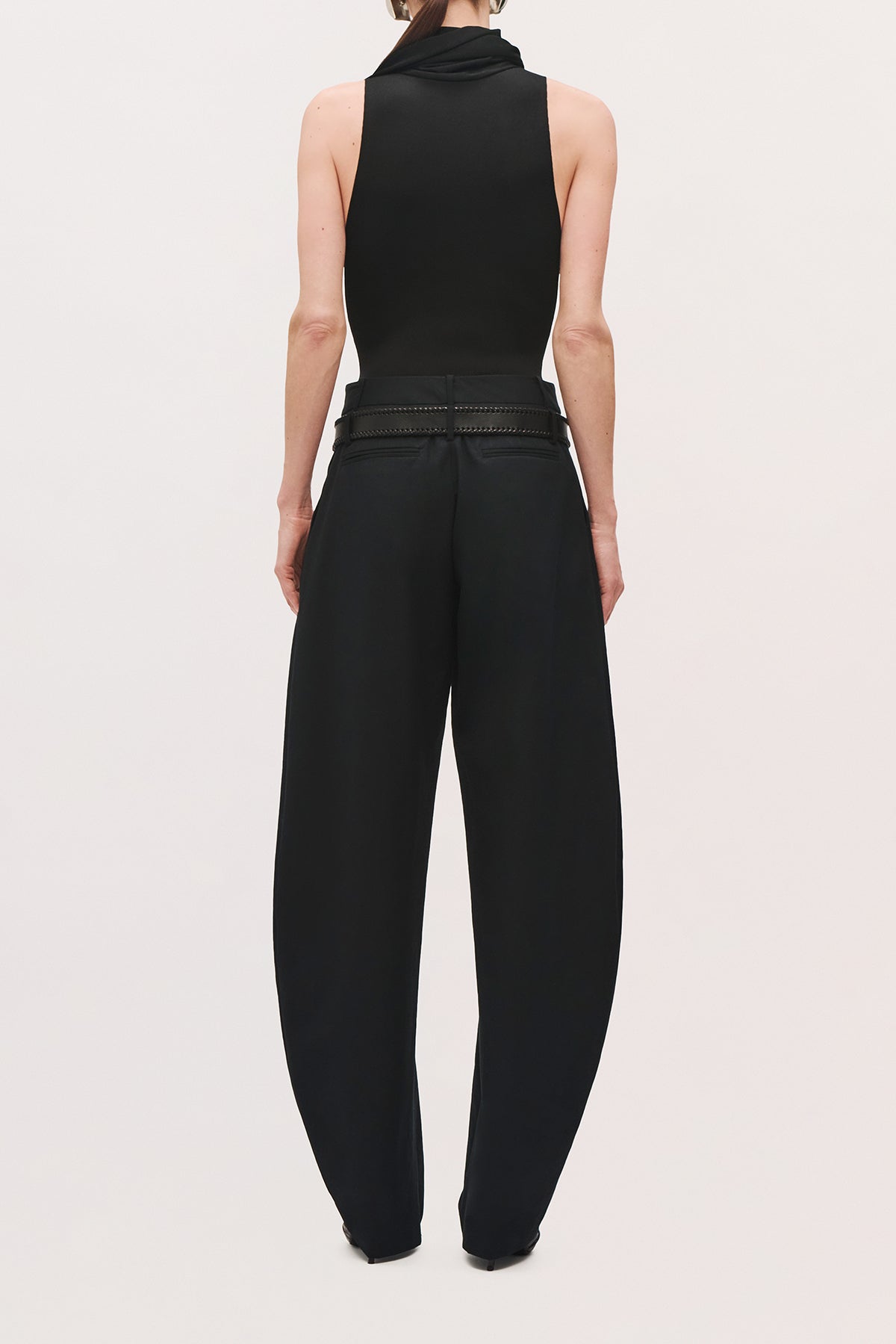 Back product view of a model wearing the Dean Pant in truffle with a low-rise waist and relaxed, curved-leg silhouette. 