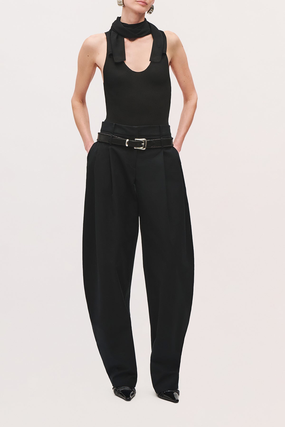 Front view of a model wearing the Dean pants in truffle with a low-rise waist and relaxed, curved-leg silhouette, and a silver belt buckle.