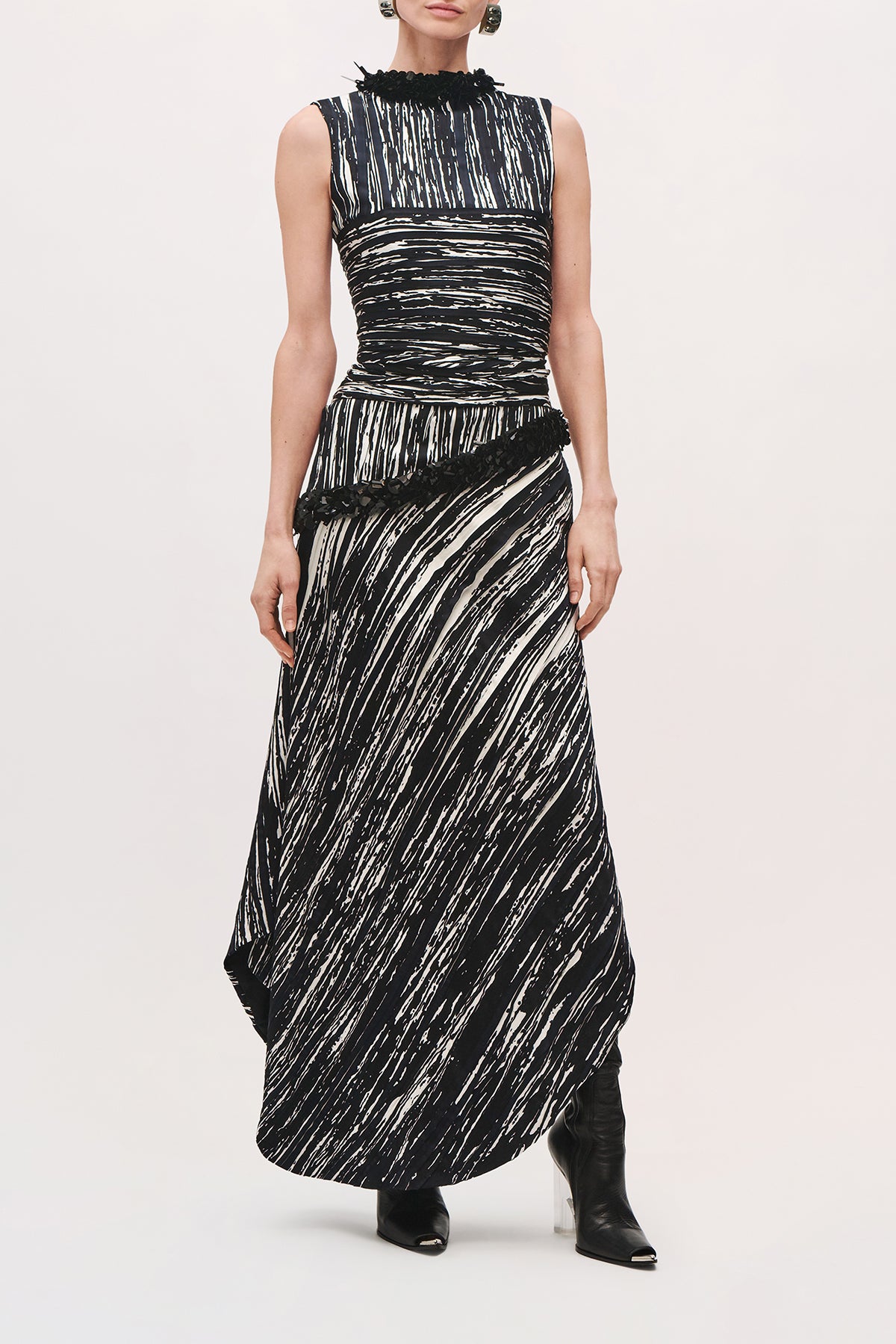 Front product view of a model wearing the Sinclair Dress in Black/White with cut of sleeves, asymmetrical skirt, and high neckline. 