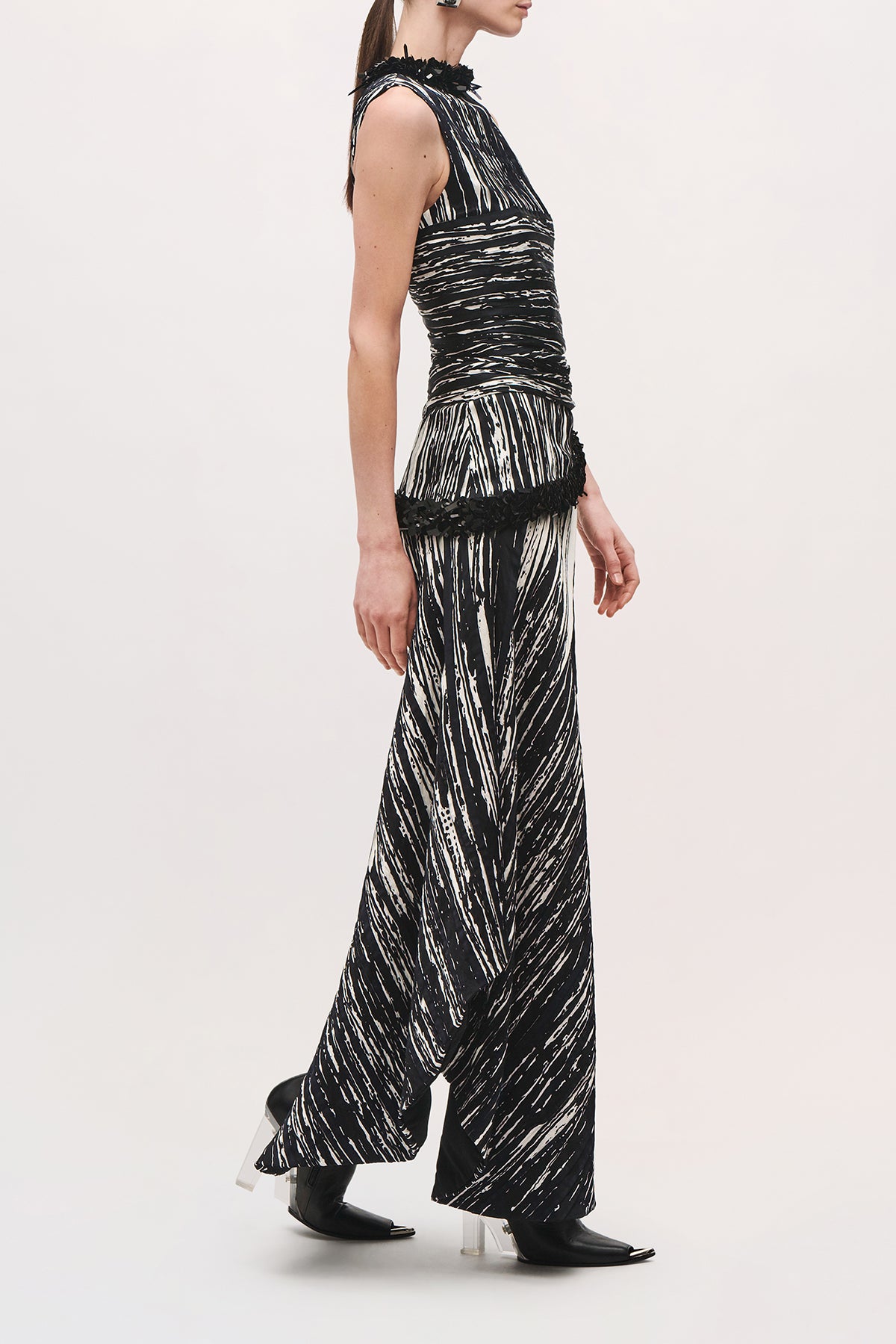 Side product view of a model wearing the Sinclair Dress in Black/White with black sequin accents on the neckline and waistline and a ruched fitted bodice. 