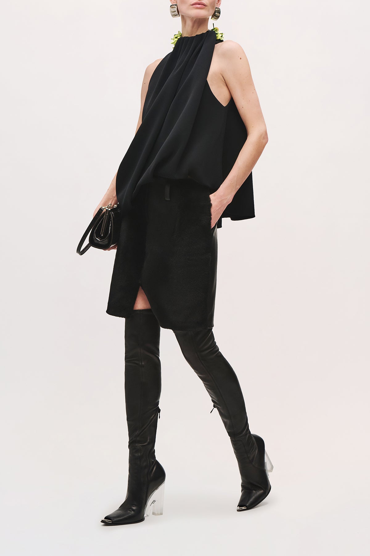 Angled front view of a model wearing the Haze Top in Black/Green;Glo, featuring a loose sleeveless silhouette, gathered neckline, black sequin shoulder detail, and softly draped asymmetric hem.