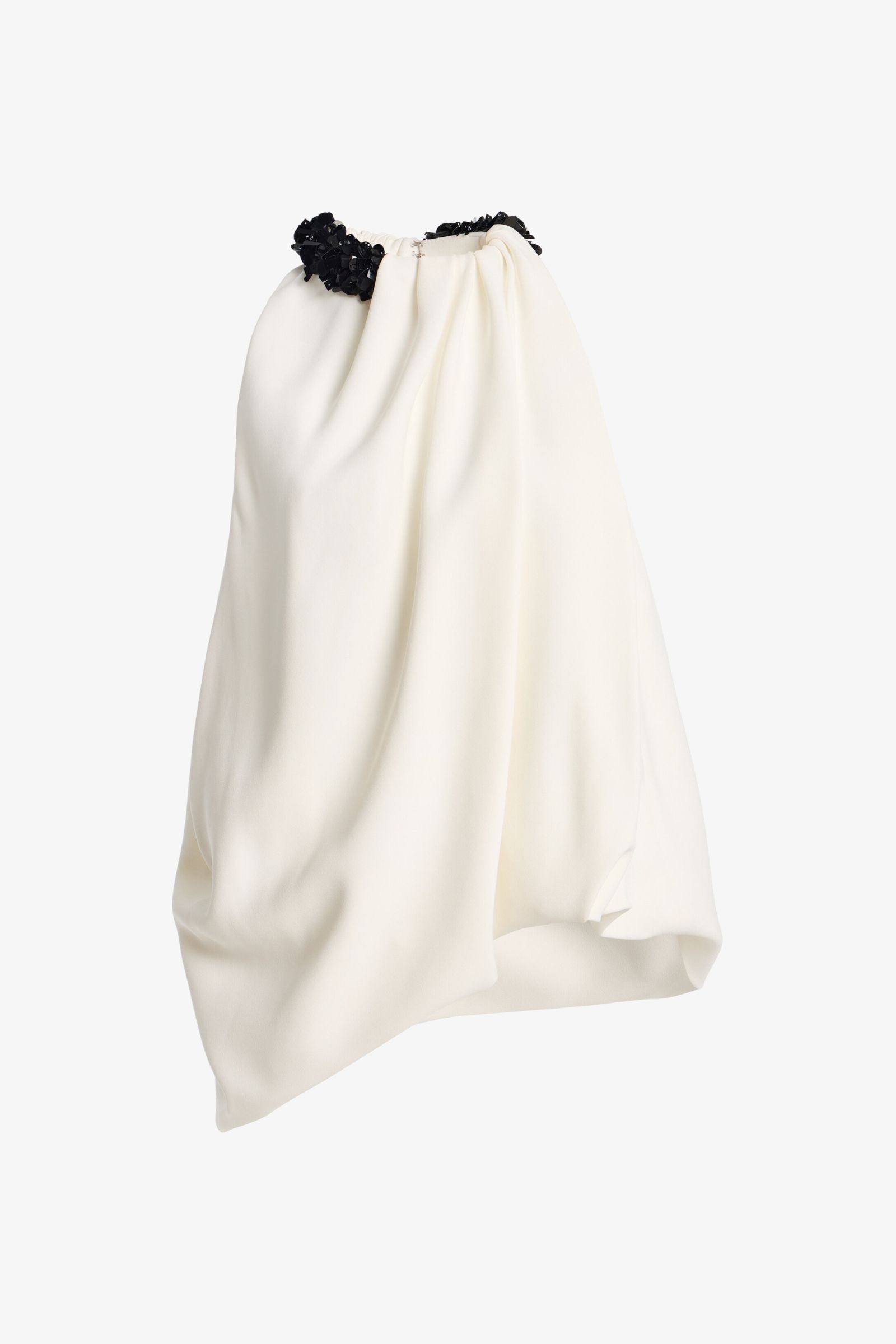 An asymmetrical draped skirt in off-white fabric with a black textured beaded waistband, shown against a plain white background.