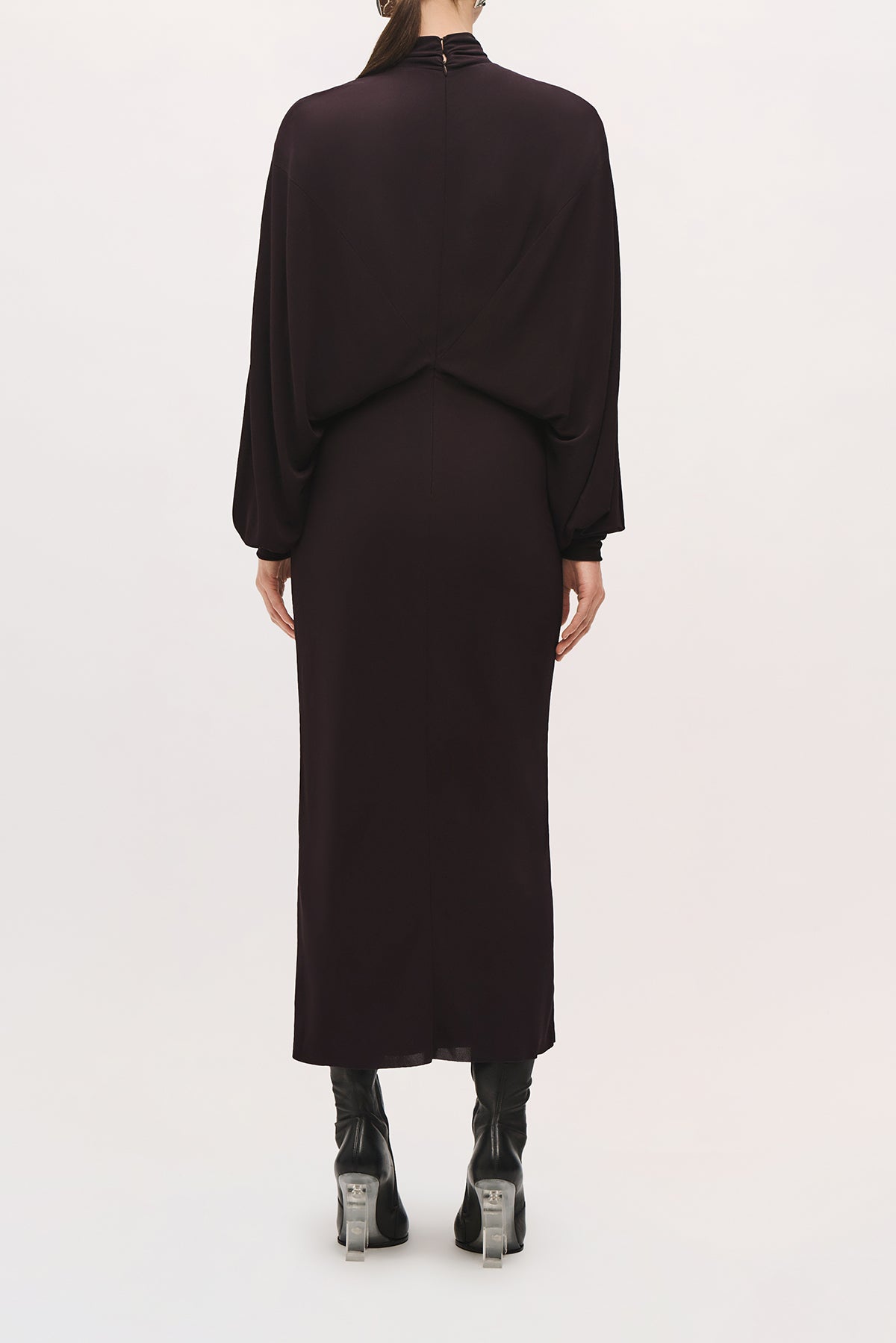 Back view of a model wearing the Helena Dress in Ganache, showing its relaxed bodice and fitted skirt. 