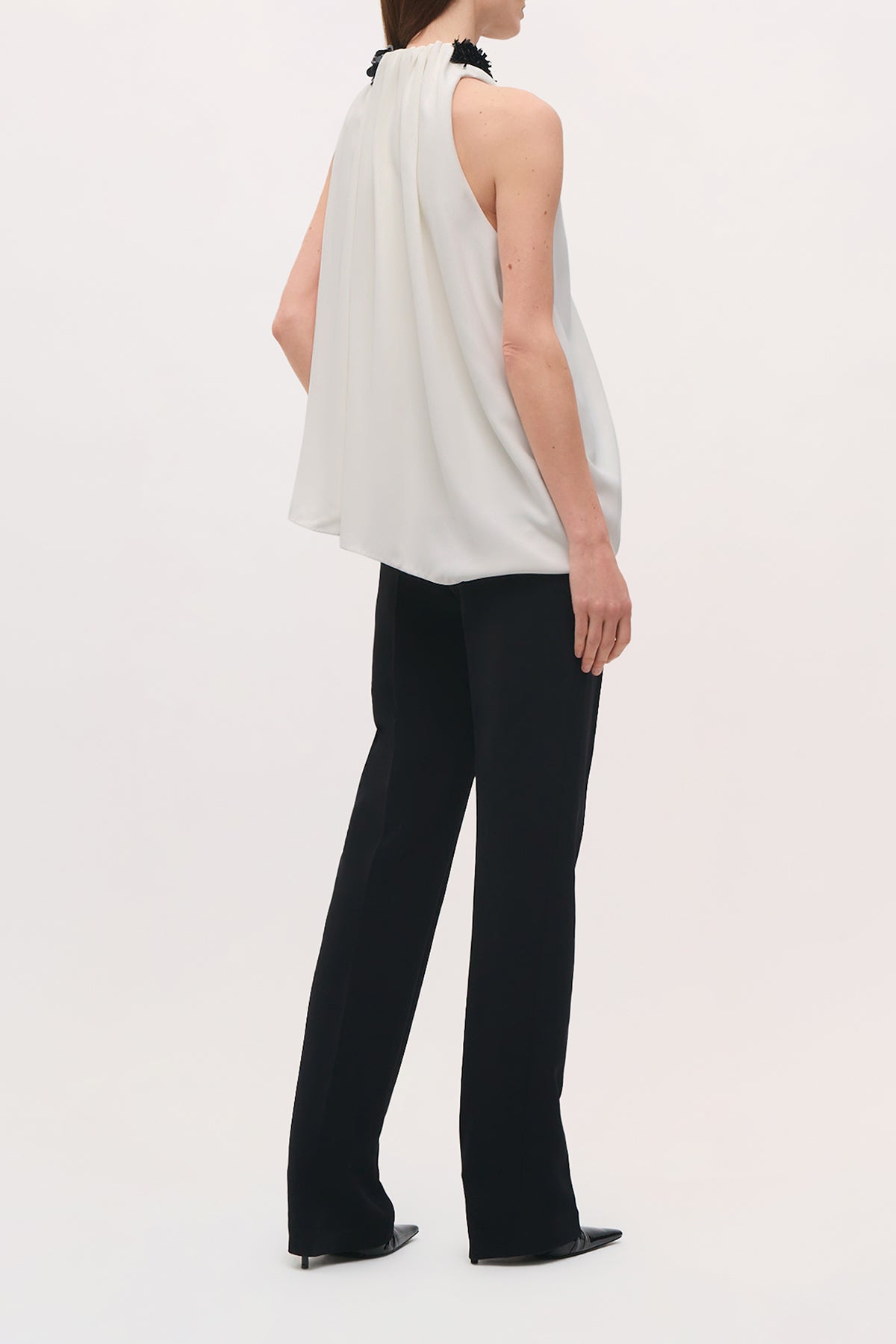 Back full body view of a model wearing the Irving Pant in black, a high-rise pant that features a straight, full-length leg and a clean tailored finish.