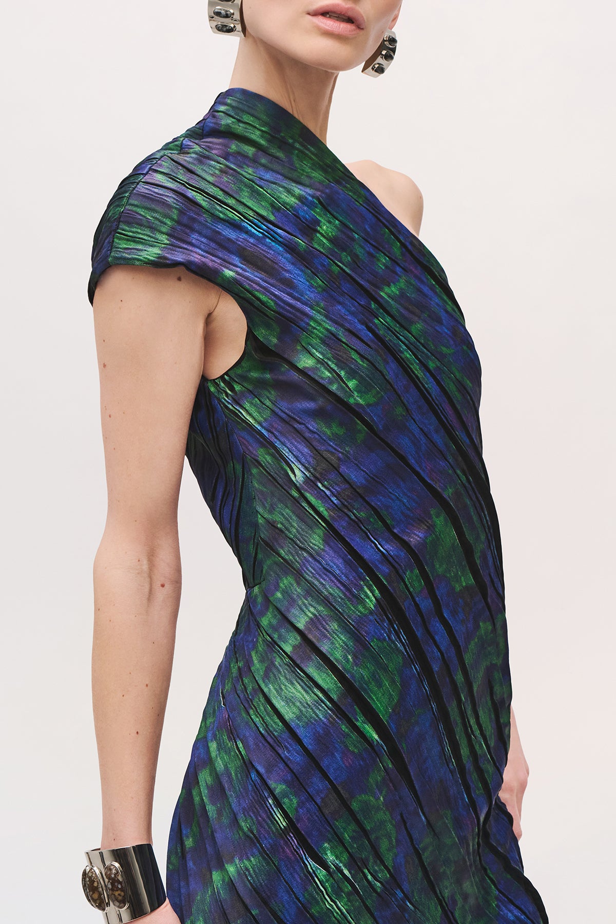 Cropped view of the side of a model wearing the Karina Dress in Blue Floral, with one draped cap sleeve, and a fitted silhouette.