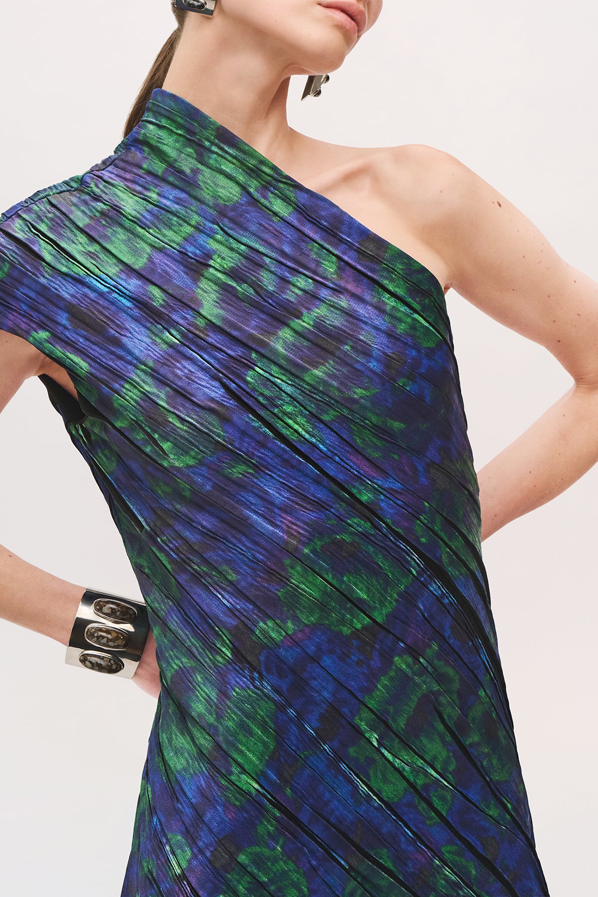 Close up of model wearing the Karina Dress in Blue Floral with one shoulder, and small pleats throughout the dress 