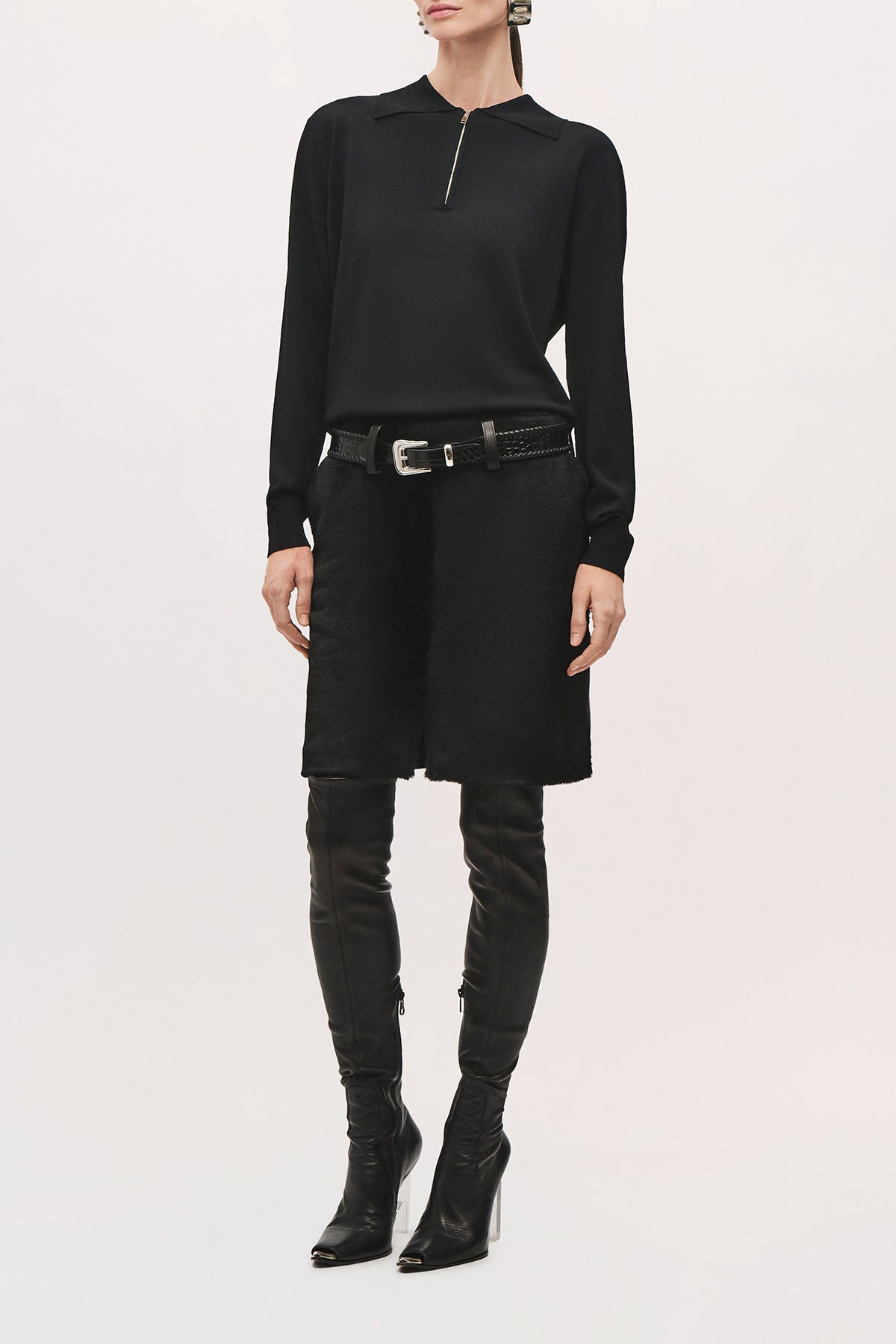  Angled front view of a model wearing the Keaton Sweater in Black, with a fitted silhouette, long sleeves, and a quarter-zip neckline.