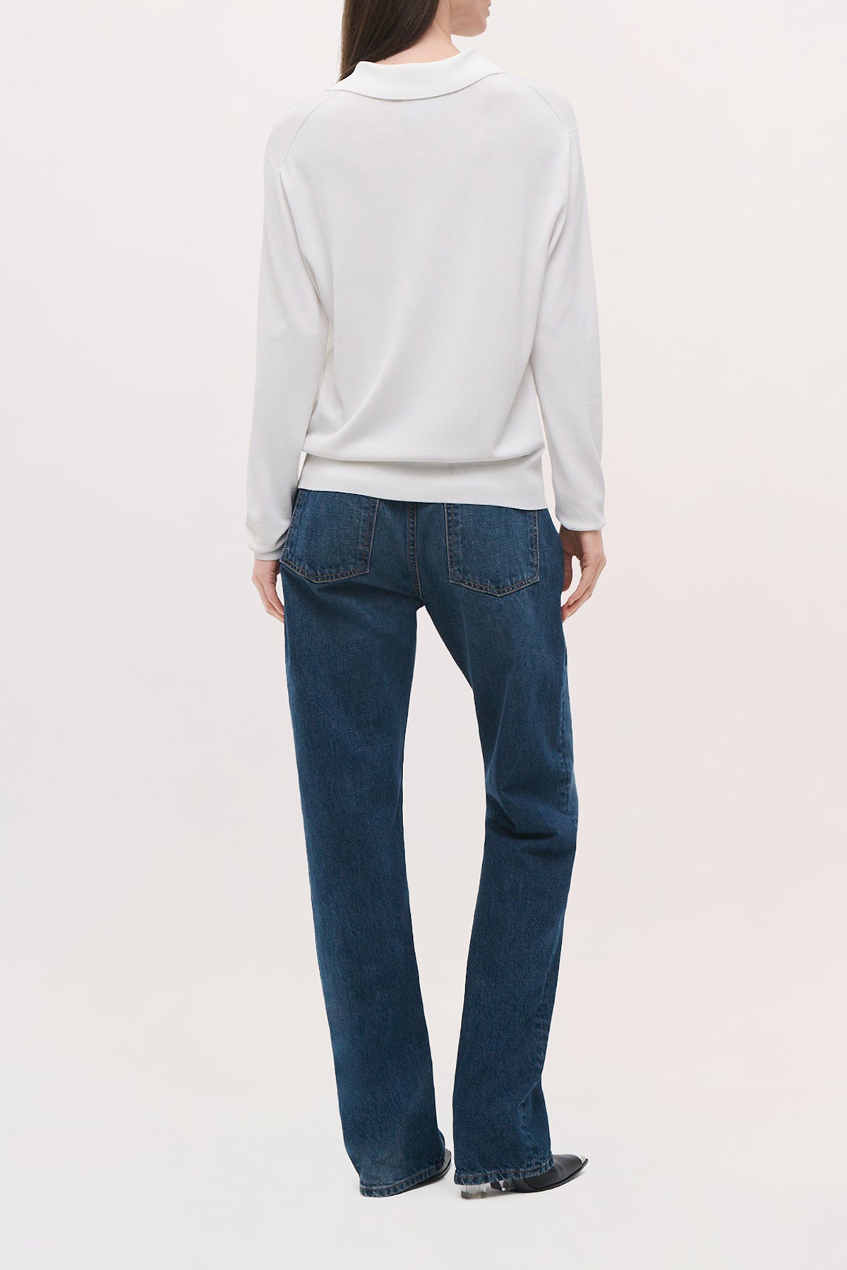 Back view of a model wearing the Keaton Sweater in white, showing its slim fit, straight hem, and long sleeves.