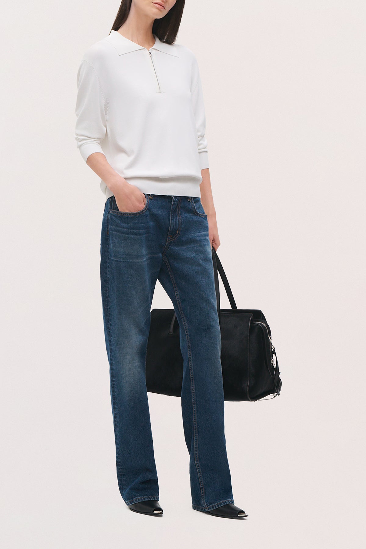 Angled front view of a model wearing the Keaton Sweater in white, with a fitted silhouette, long sleeves, and a quarter-zip neckline.