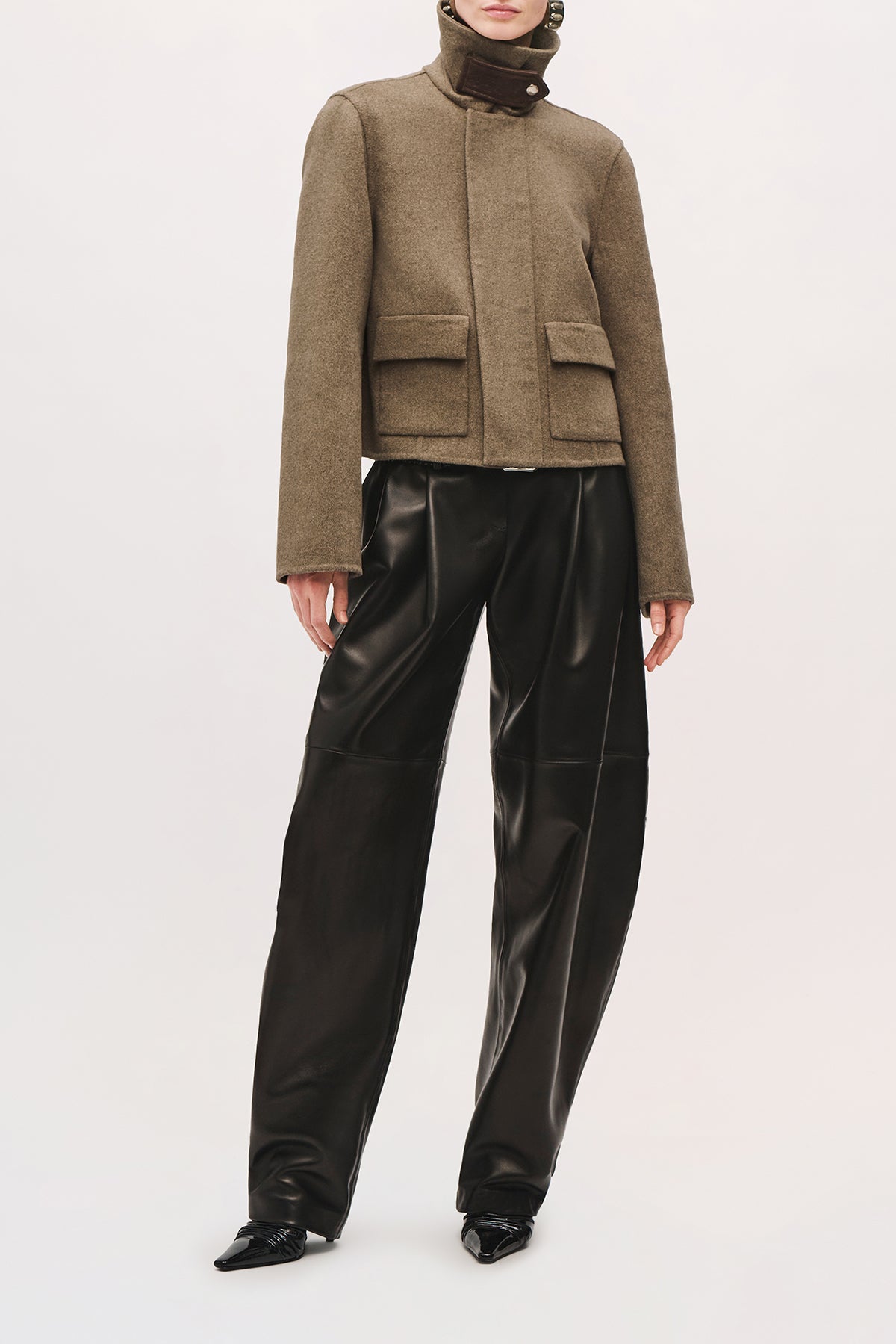 Front view of a model wearing the Remi Jacket in Truffle, with a popped pointed collar, two pockets, and a cropped fit.