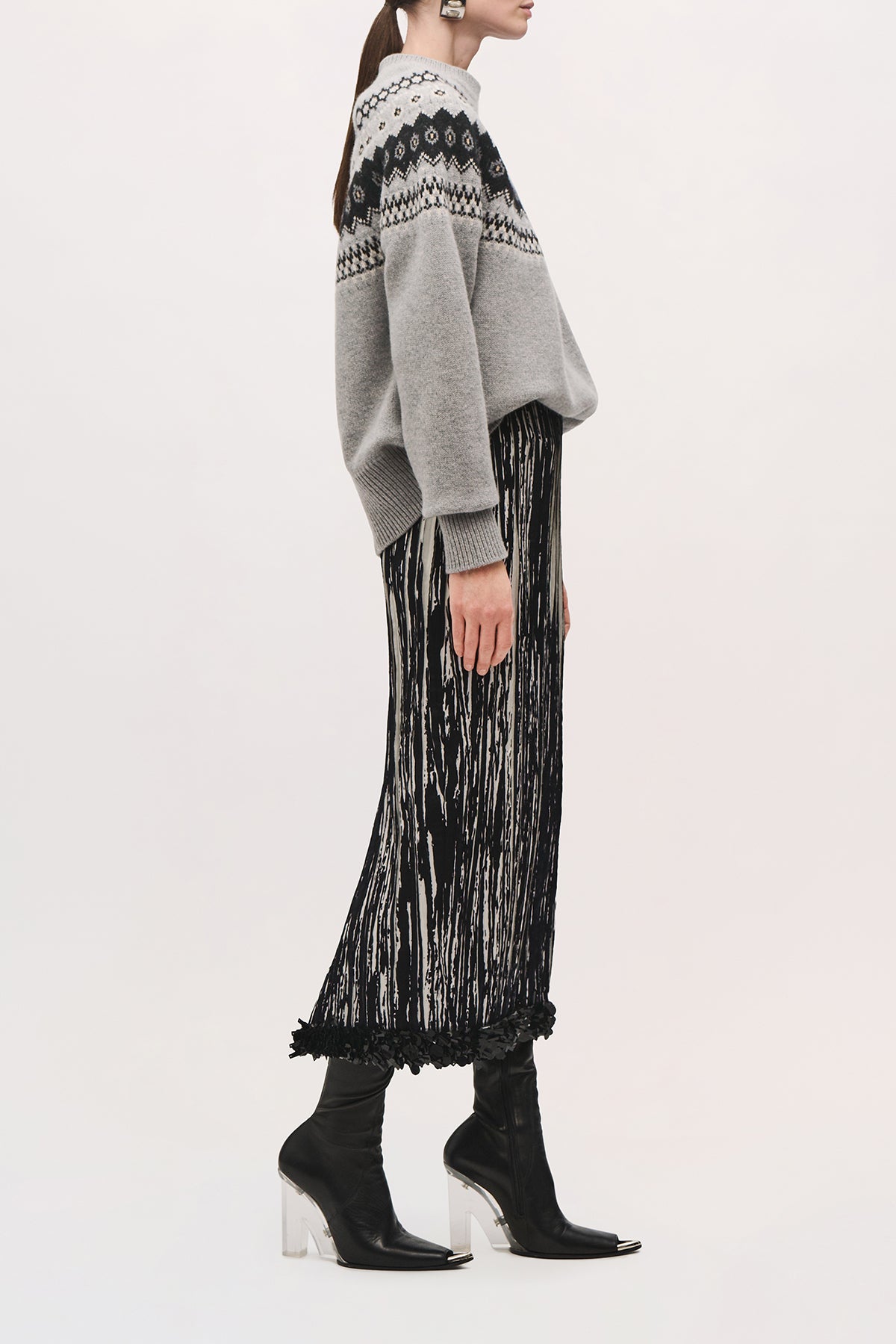 Side view of a model wearing the Sinclair Skirt in Black/White, a midi-length skirt with a black sequin hem, and a straight fit.